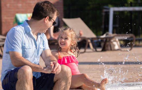 Dad with daughter splashing in pool